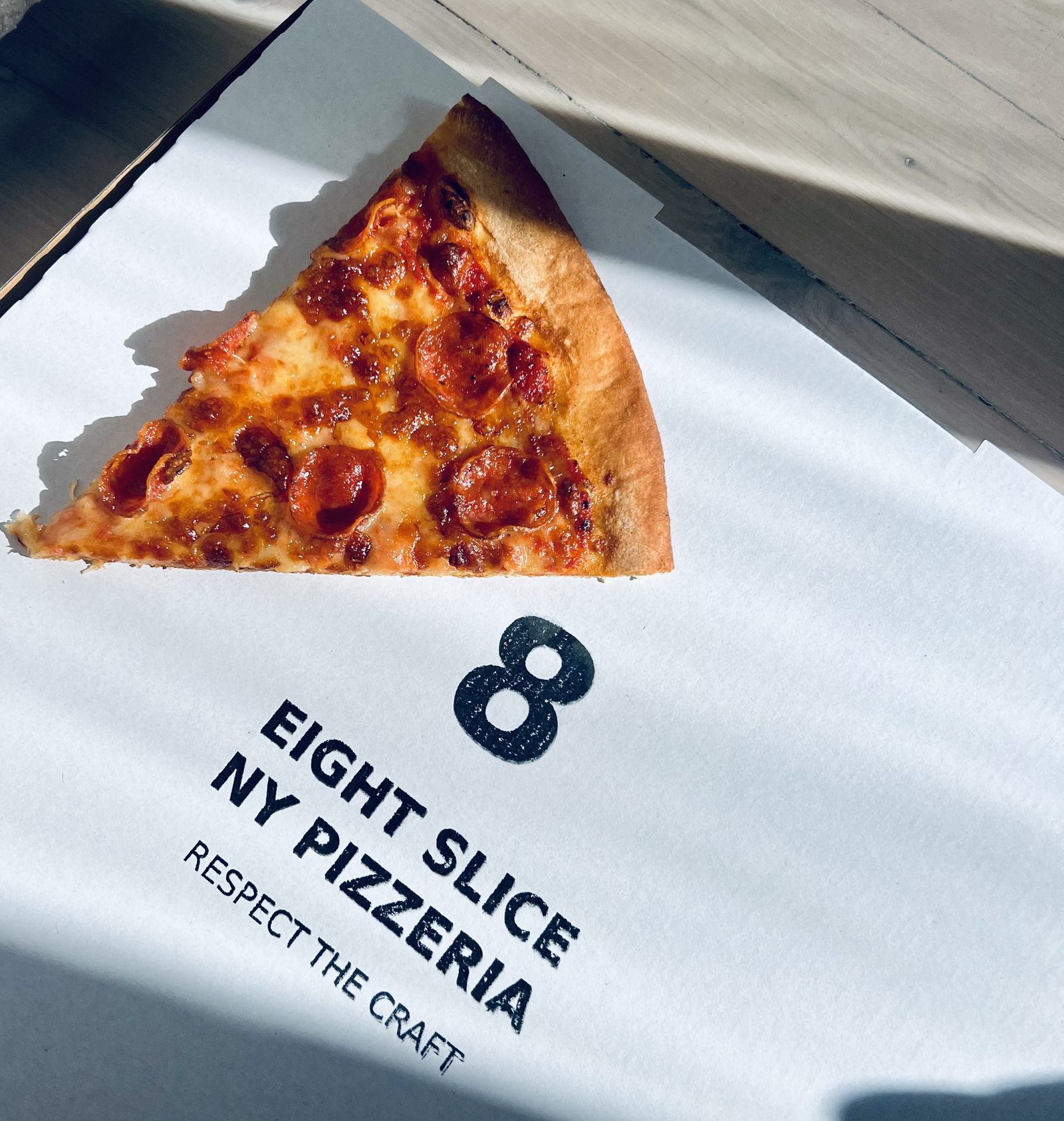 Eight Slice NY pepperoni slice on branded paper